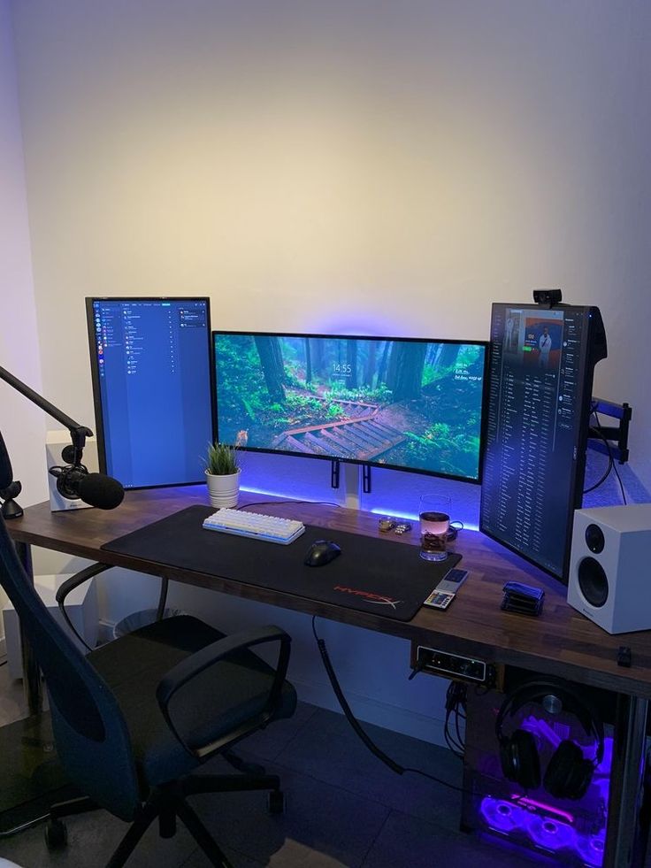 two computer monitors sitting on top of a wooden desk