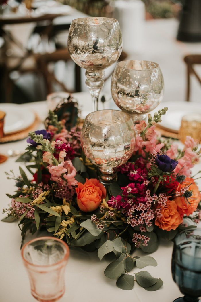 an arrangement of flowers and wine glasses on a table at a wedding or reception party