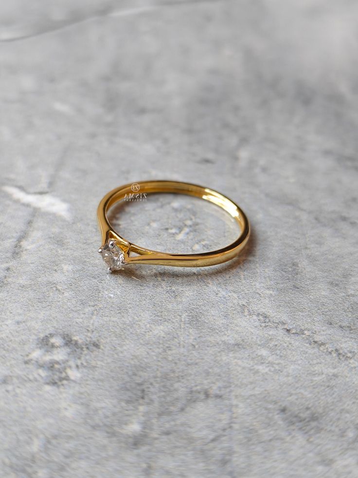 a gold ring sitting on top of a stone floor with a diamond in the middle