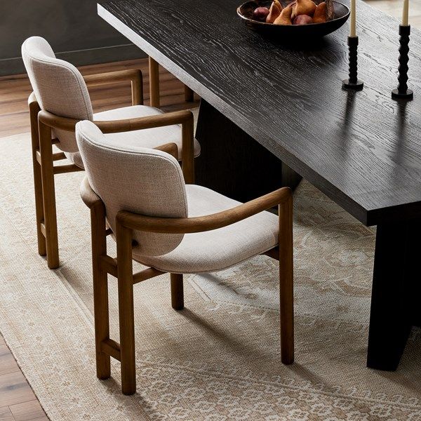 a dining room table with two chairs and a bowl of fruit on the table next to it