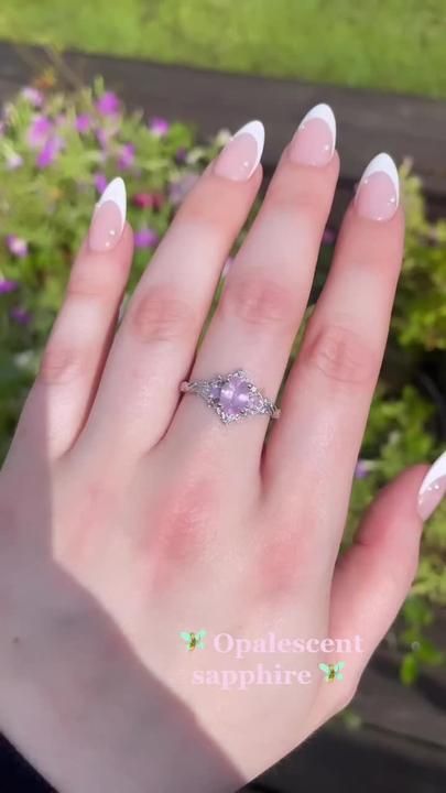 a woman's hand with white nails and a ring on it