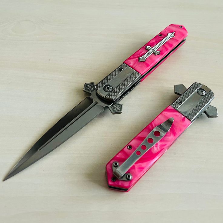 two pink and black knifes sitting next to each other on top of a table