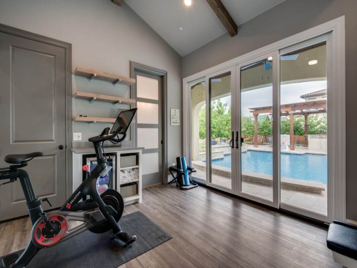 an indoor gym with exercise equipment and sliding glass doors leading to a swimming pool area