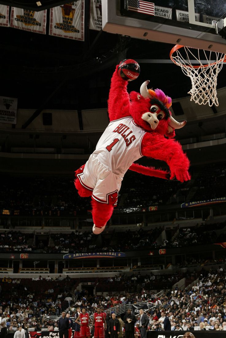 the mascot is jumping up into the air to dunk the basketball in front of him