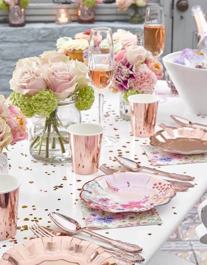 the table is set with pink and white flowers in vases, silverware, and plates