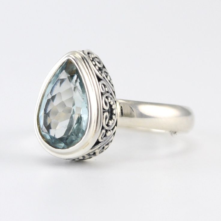 This genuine tear shaped aquamarine gem is set in a sterling silver bezel setting. Granulated silver scroll and bead work decorate the bezel. Handmade ring is a size 7 and can be sized. To clean: simply polish silver when needed with a jewelry polishing cloth. Style Number: 13121 Metal: 925 Sterling Silver Gemstone: Genuine Aquamarine Dimensions: 1/2 inch high and 3/8 inch wide Handmade in Bali, Indonesia Anniversary Blue Topaz Teardrop Ring, Anniversary Teardrop Blue Topaz Ring, Sterling Silver Teardrop Topaz Ring Gift, Sterling Silver Teardrop Topaz Ring For Anniversary, Teardrop Topaz Ring For Anniversary, Elegant Teardrop Topaz Ring In Sterling Silver, Anniversary Teardrop Topaz Ring In Sterling Silver, Anniversary Teardrop Topaz Ring, Silver Teardrop Topaz Promise Ring