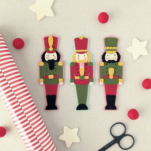 three felt toy soldiers are next to a pair of scissors