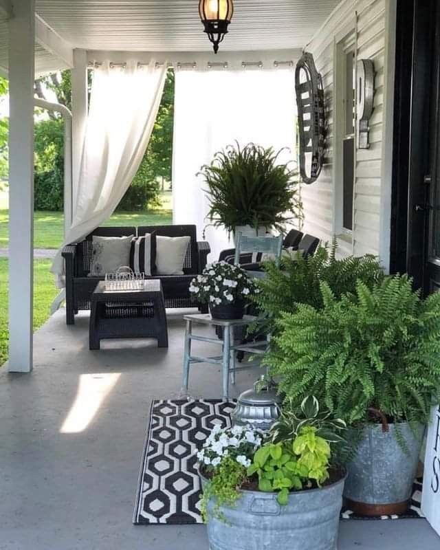 a porch with potted plants and chairs on the front porch, along with an awning