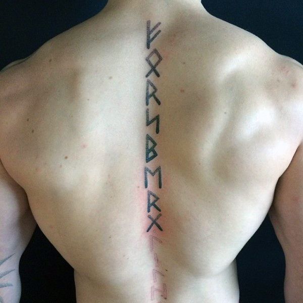 the back of a man's upper body with an ancient writing tattoo on it