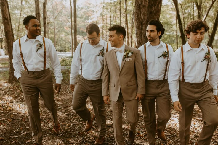 a group of young men standing next to each other in the middle of a forest