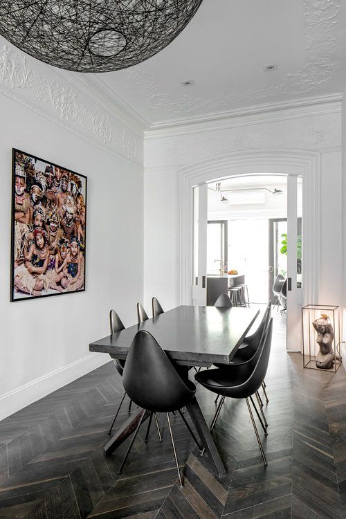 a dining room table with black chairs and pictures on the wall in front of it