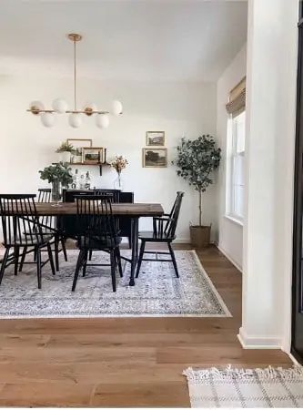 a dining room table with black chairs and white rug