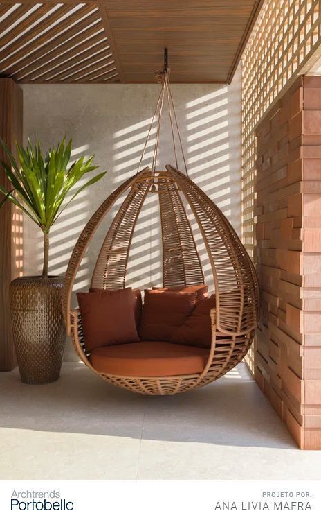 a hanging chair in the corner of a room next to a potted palm tree