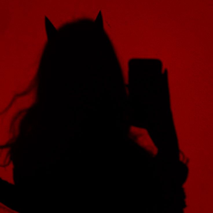 the silhouette of a woman holding a cell phone in front of her face, against a red background