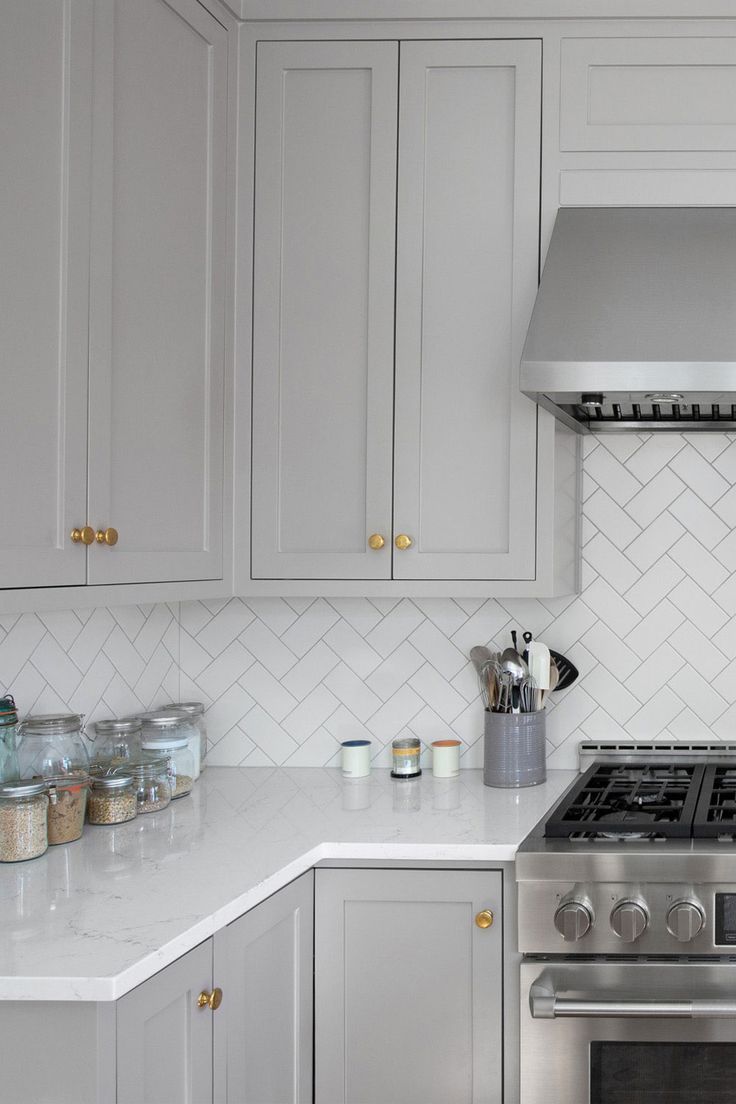 a kitchen with white cabinets and stainless steel stove top oven in the center, surrounded by marble counter tops