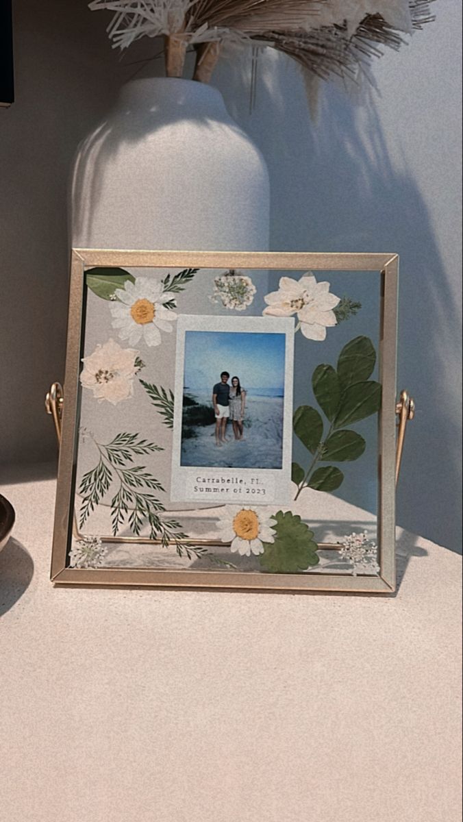 a photo frame sitting on top of a table next to a vase with flowers in it