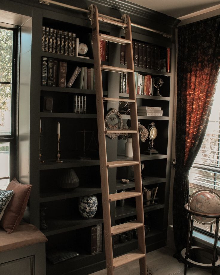 a ladder leaning up against a bookshelf in a room with windows and curtains