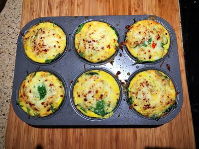 a muffin tin filled with lots of food on top of a wooden cutting board