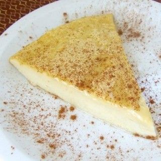 a piece of cheesecake on a white plate with cinnamon sprinkles around it