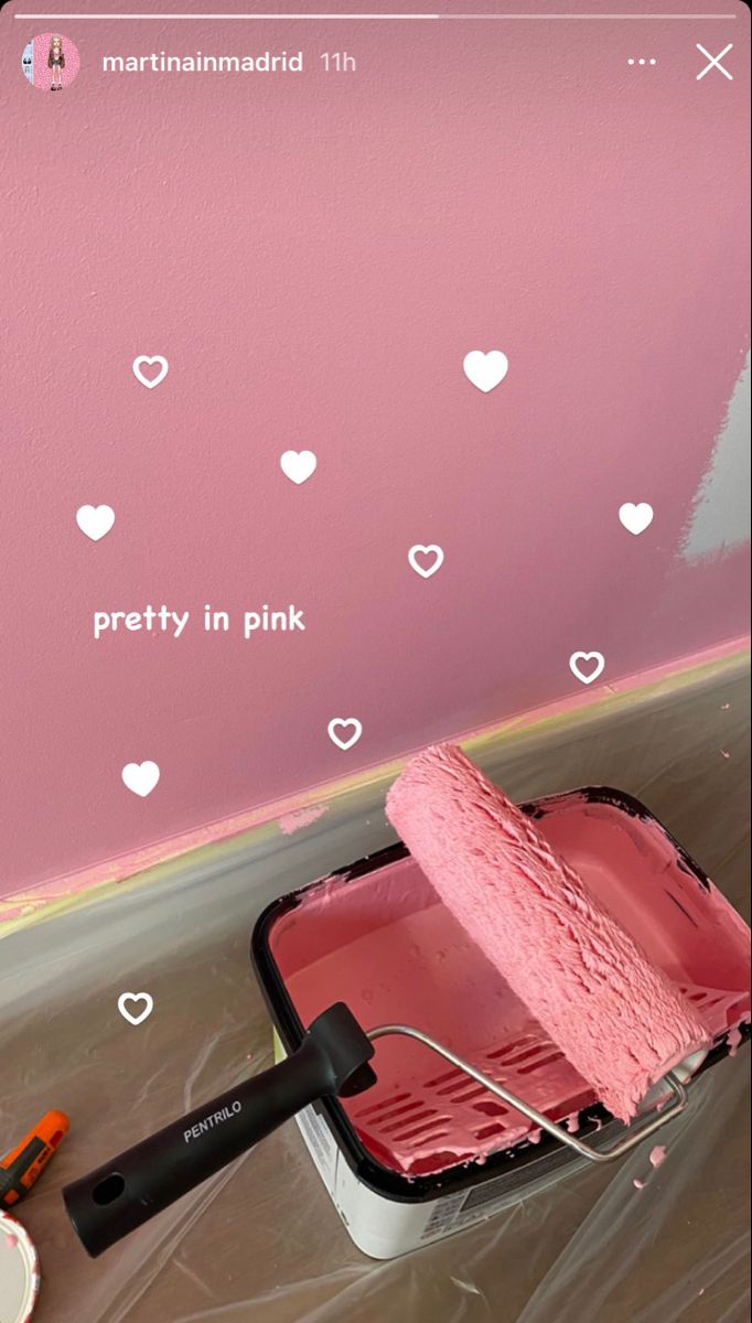 a pink wall with hearts painted on it and a paint roller in the foreground