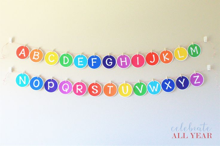 a colorful paper garland with letters and numbers hanging on the wall in front of a white wall