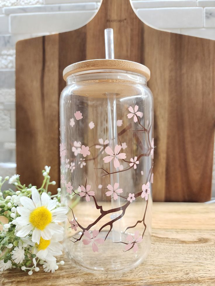 a glass jar with flowers painted on it