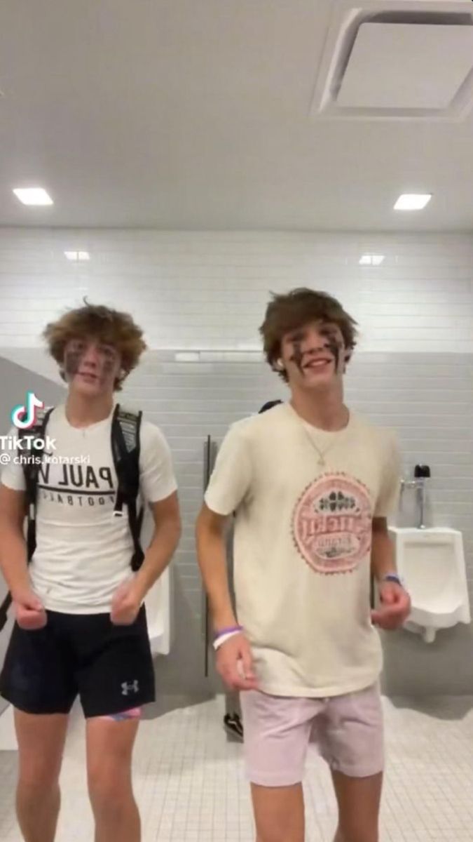 two young men standing next to each other in a bathroom