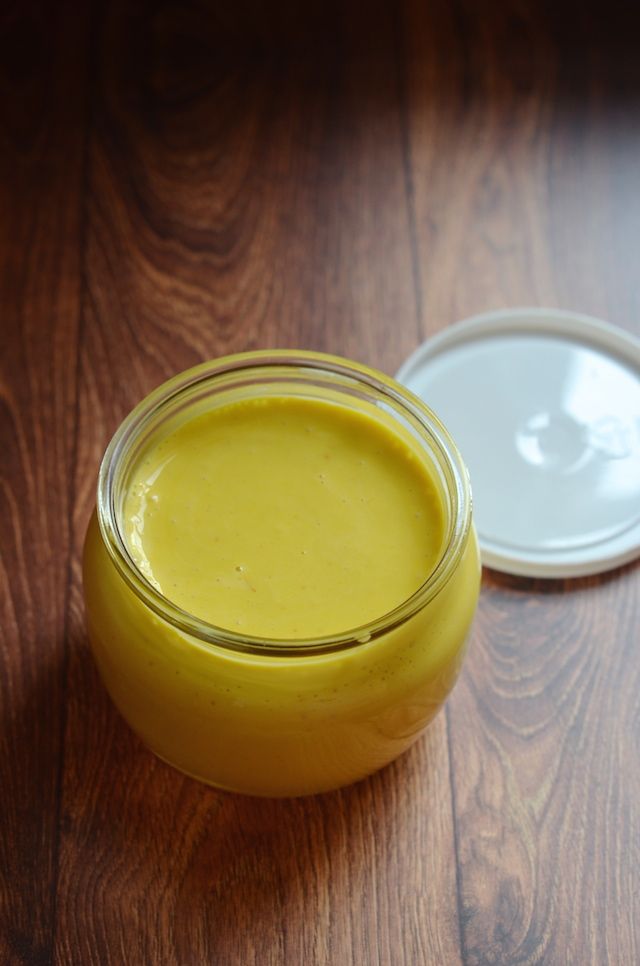 a glass jar filled with yellow liquid sitting on top of a wooden table