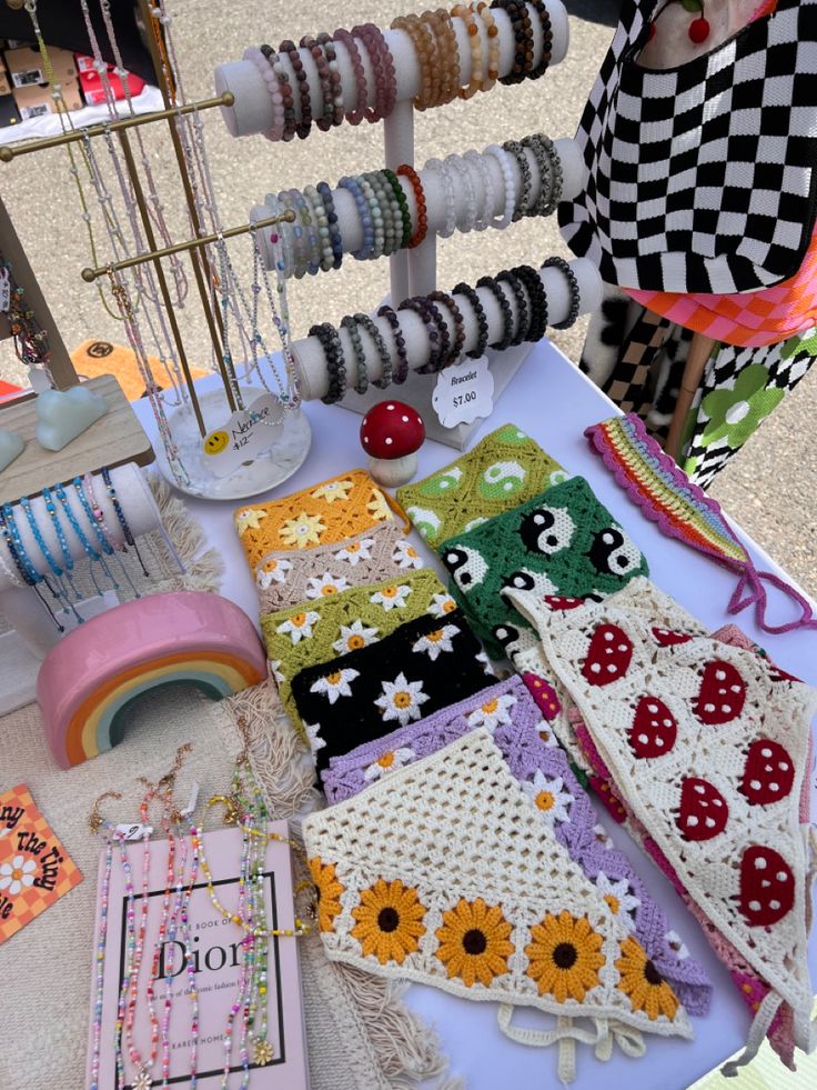 an assortment of bracelets and necklaces displayed on a white table with other items