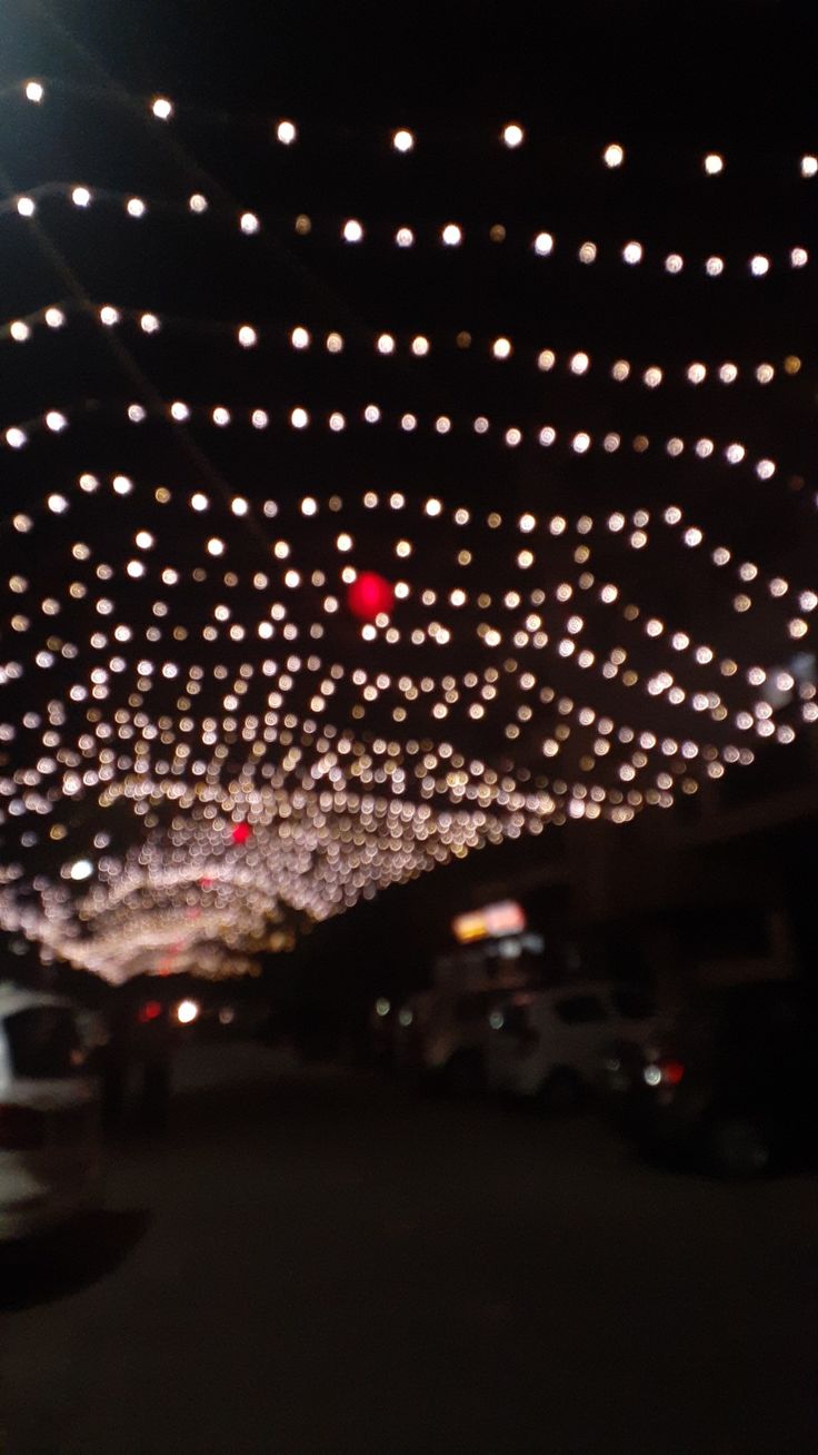 the lights are hanging from the ceiling in the parking lot as cars drive down the street