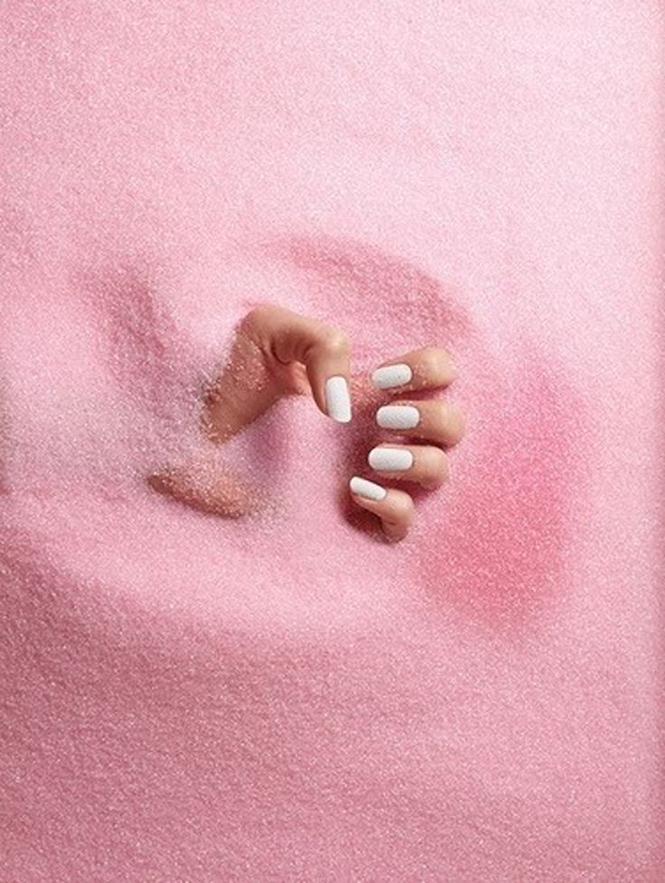 someone holding their hand in the sand on top of a pink blanket with white writing