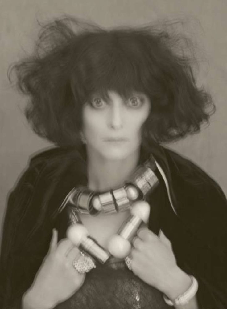 a black and white photo of a woman with her hair blowing in the wind, holding two small objects