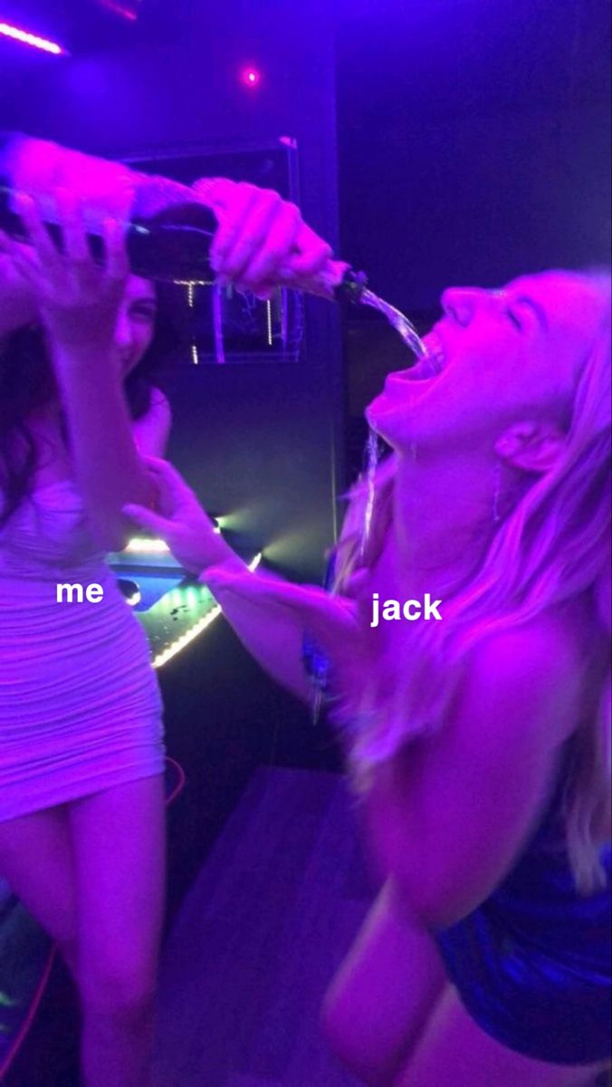 two beautiful young women standing next to each other in front of a mirror drinking from bottles