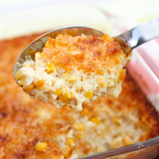 a spoon full of macaroni and cheese being lifted from a casserole dish