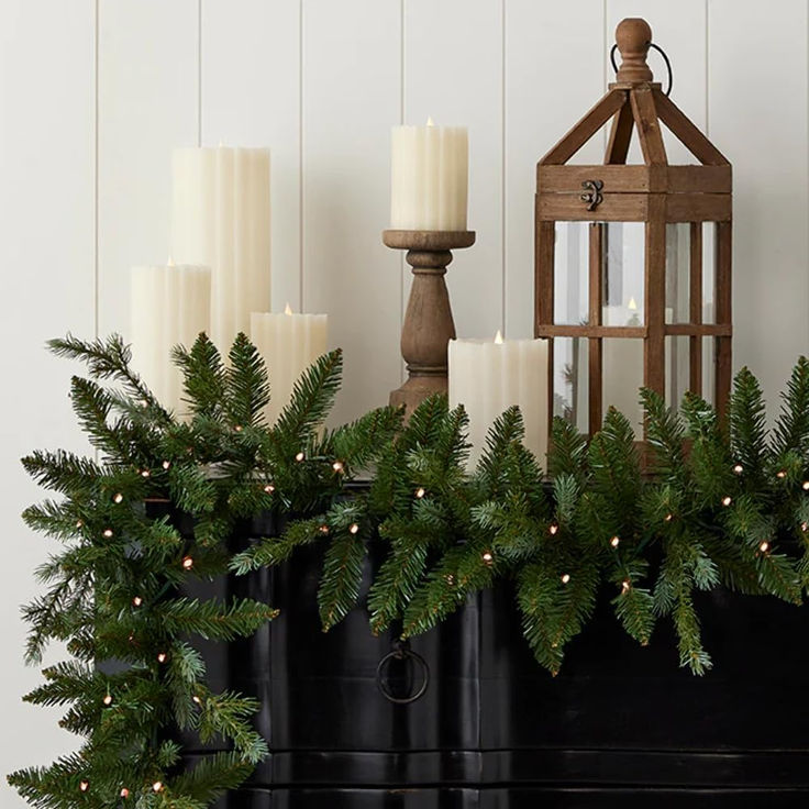 a christmas mantle with candles and garland on it