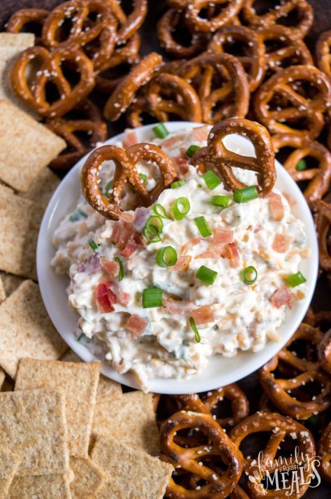 a bowl of dip surrounded by pretzels and crackers