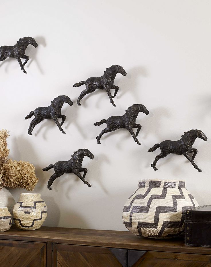 there are many horse figurines on the wall next to vases and flowers