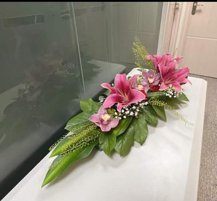 a bouquet of pink flowers sitting on top of a white counter next to a glass door