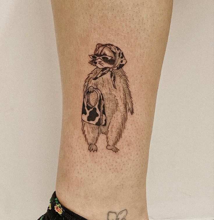 a small raccoon tattoo on the leg of a woman's lower body