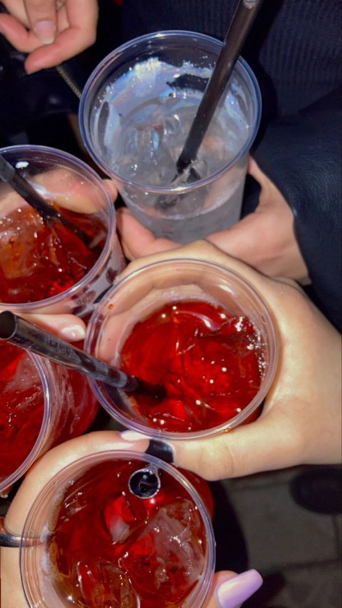 four people are holding their hands together with cups full of liquid and spoons in them