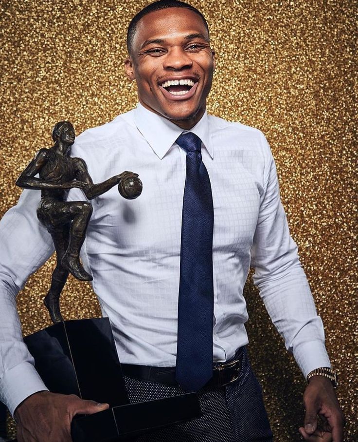 a man in a white shirt and blue tie is holding a trophy while smiling at the camera