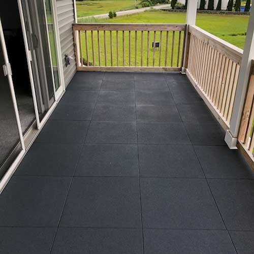 an empty porch with black tile and sliding glass doors on the side of the house