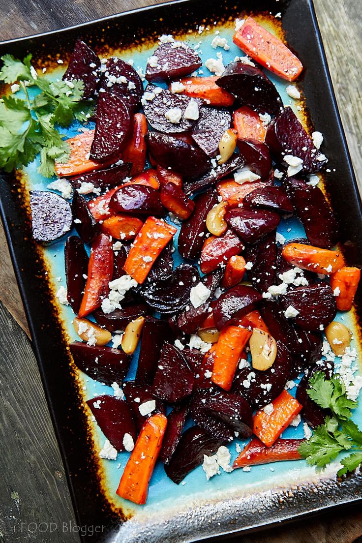 roasted beets and carrots with parmesan cheese on a blue plate sitting on a wooden table