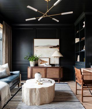 a living room with black walls and white rugs on top of the carpeted floor