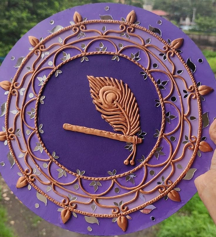 a person holding up a purple and gold clock