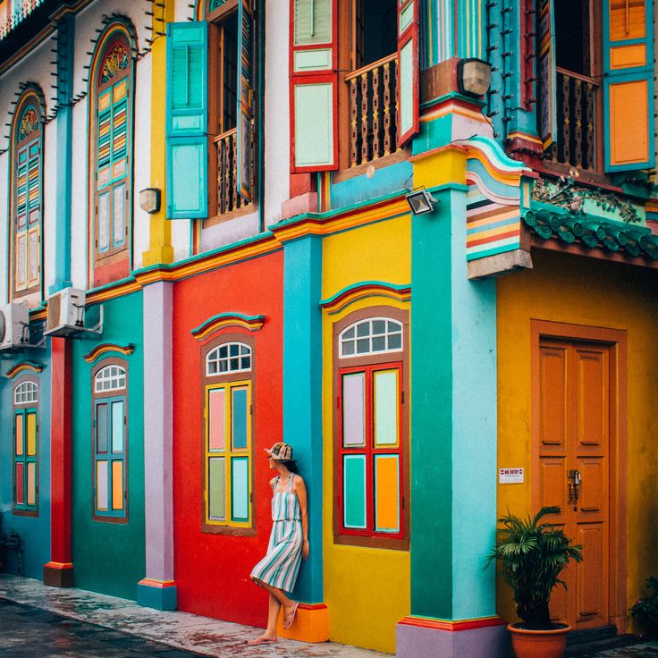 a woman standing in front of a multi - colored building