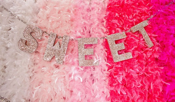 pink and white feathers with the word sweet spelled in silver letters on it's side