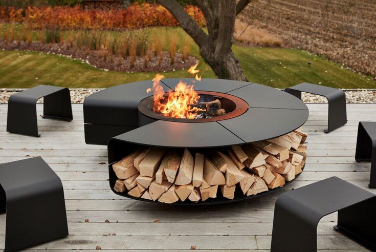 a fire pit sitting on top of a wooden deck next to black chairs and tables