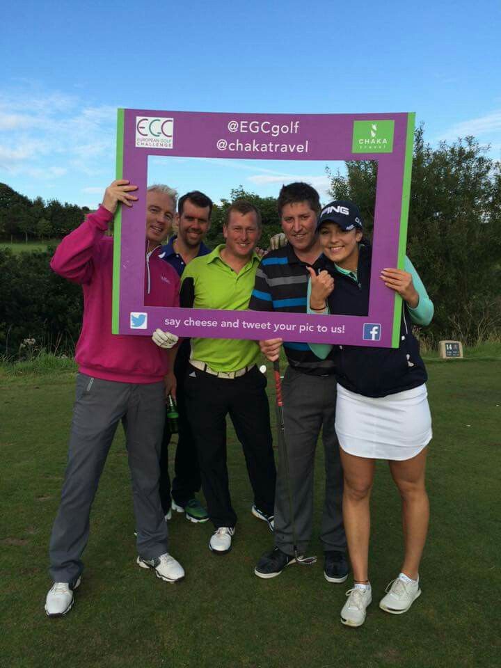 some people are posing for a photo with a big sign in front of them on the golf course