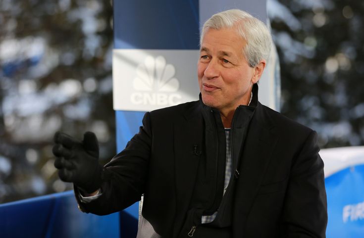 an older man in a black suit and white shirt is talking to someone with his hand out